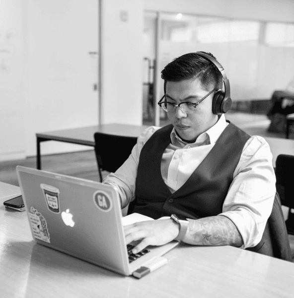 Concentrated bootcamp participant with headphones typing on a laptop, immersed in learning new coding skills.