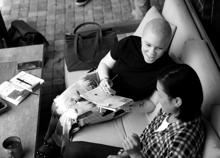 A couple of people discuss data literacy training while sitting on a couch.