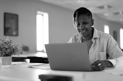 A woman sitting down using a laptop searching for tech skills training.