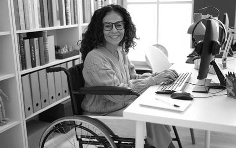 Middle age hispanic woman teacher using computer sitting on wheelchair at library university