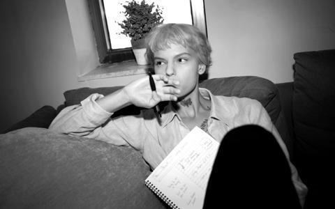 Person deep in thought, holding a pen to their mouth while going through notes on a sofa, reflective of the studious environment in Paris.